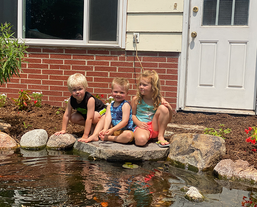 Children playing near a backyard pond